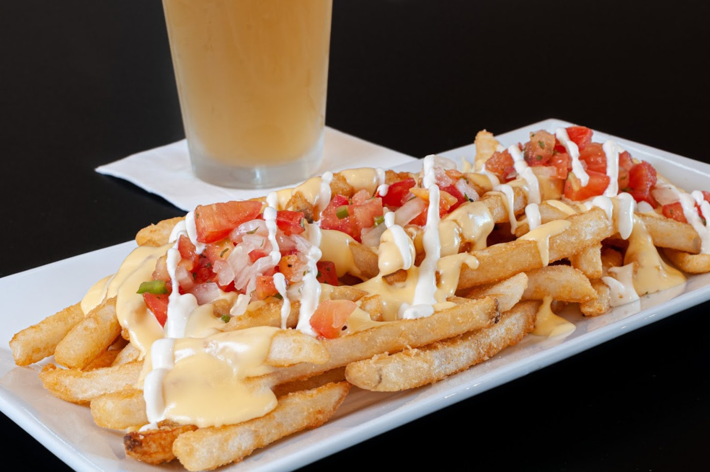 Fries with garlic and tomato, and a beer behind